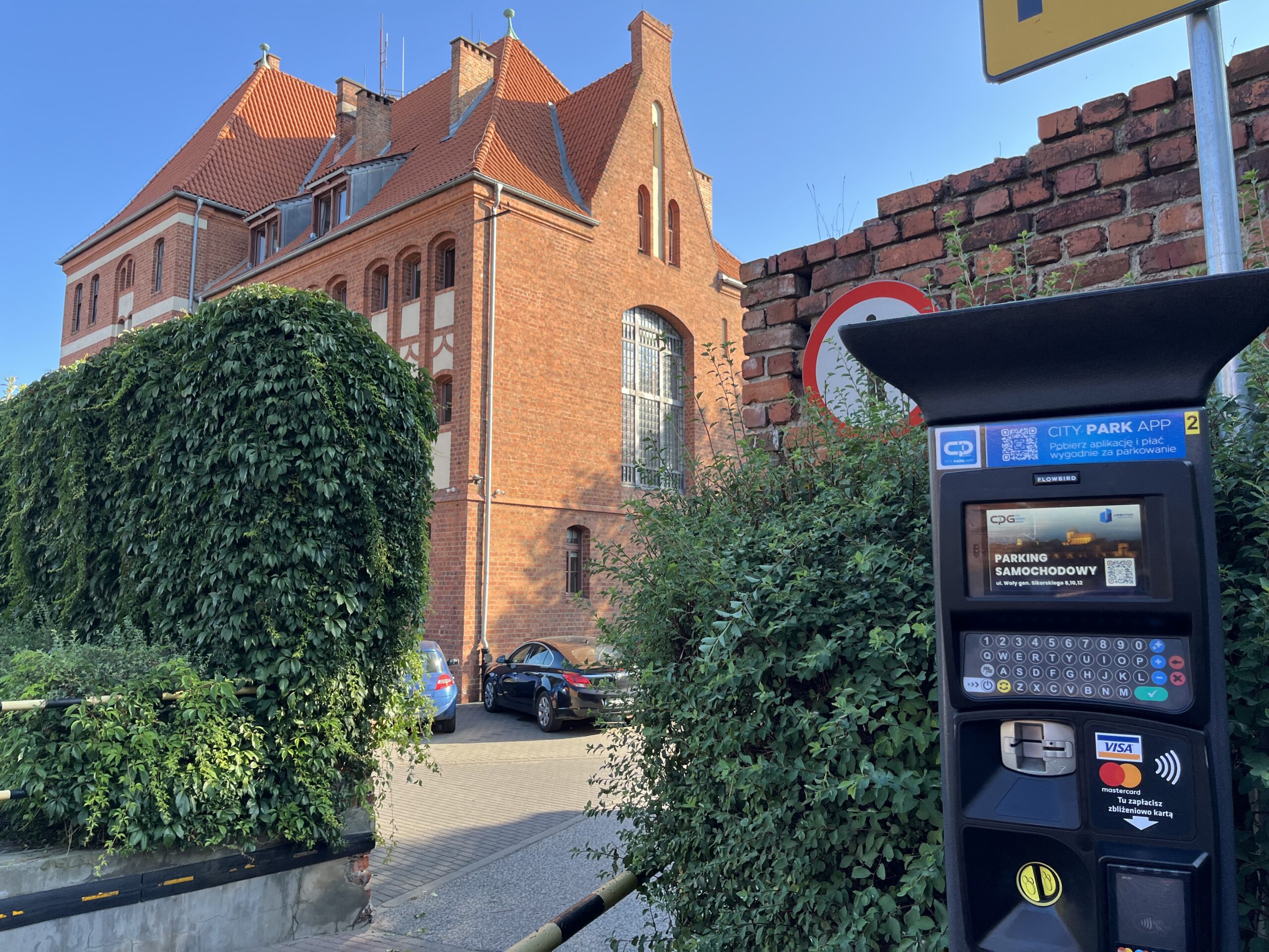 na pierwszym planie zdjęcie parkomatu w tle widoczny parking przy ul. Sikorskiego 8 w Toruniu